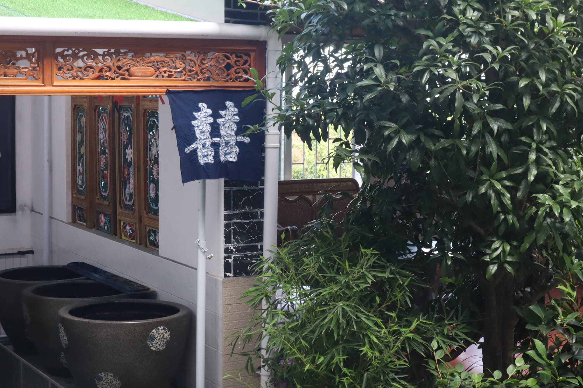 Courtyard of the Zhoucheng dye house, with large dye vats beneath a tie-dyed double-happiness banner
