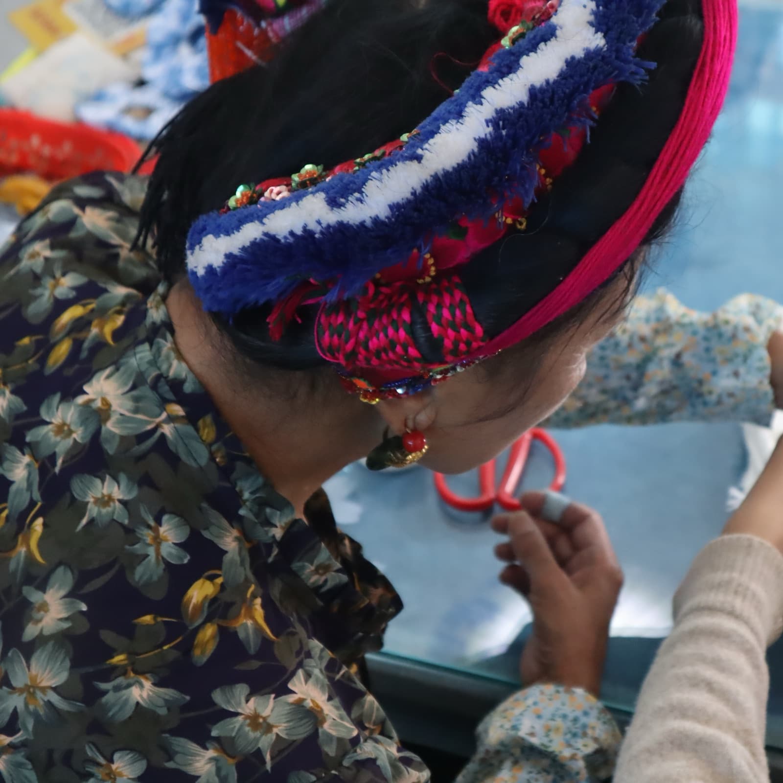 The grandmother in her Bai headdress leaning over a student's work