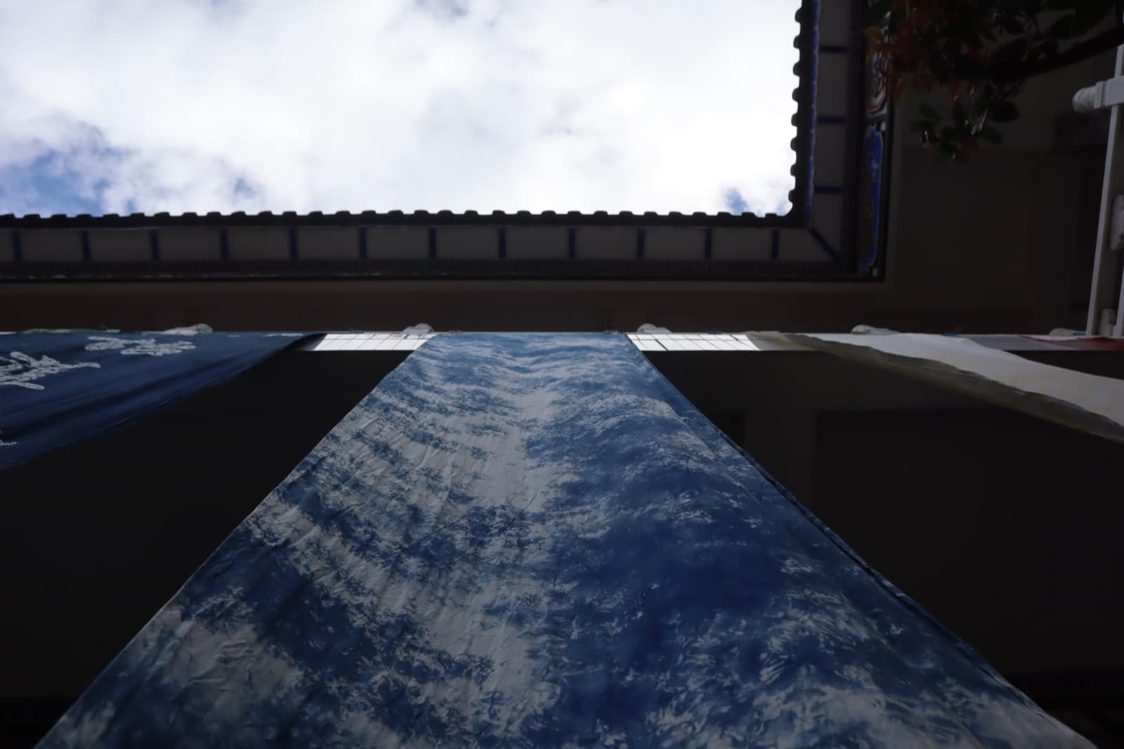 Indigo-dyed cloth hanging to dry in the workshop courtyard, seen from below