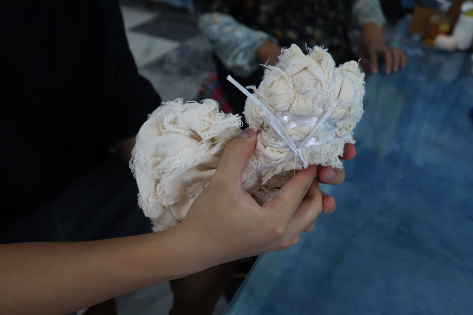 A tied bundle of white cotton held up before dyeing