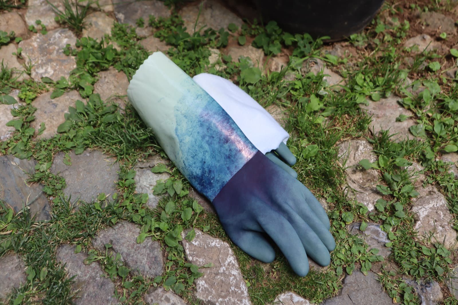 A pair of dye-stained work gloves resting on stone